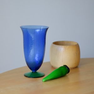 Blå glasvas på grön fot